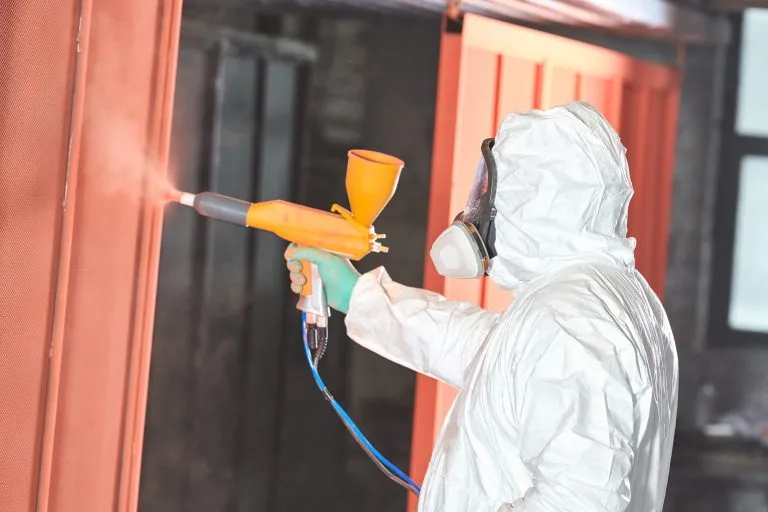 Industrial technician applying protective powder coating to metal surfaces during industrial painting in Longwood, FL