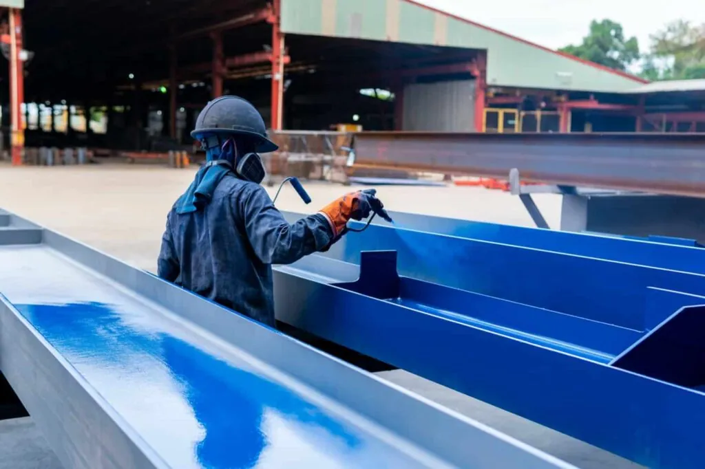 Industrial worker applying protective coating to structural steel beams during industrial painting in Longwood, FL